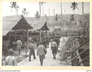 MUSCHU ISLAND, NEW GUINEA. 1945-10-10. MAJOR E.S. OWENS, ASSISTANT ADJUTANT AND QUARTERMASTER GENERAL, HEADQUARTERS 6 DIVISION, MAKING AN INSPECTION OF ORDERED IMPROVEMENTS TO THE COMPOUND AND ..