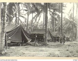 ALEXISHAFEN, NEW GUINEA. 1944-09-14. NX110641 CORPORAL J.R. BARNES (1) AND N238625 PRIVATE R.G. MCCANN (2) WALKING THROUGH THE MEN'S LINES IN THE CAMP AREA OF THE 133RD BRIGADE ORDNANCE FIELD PARK