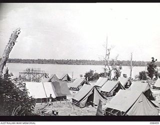 KAVIENG, NEW IRELAND, 1945-10-26. AUSTRALIAN NEW GUINEA ADMINISTRATIVE UNIT (ANGAU) CAMP ON THE FORESHORE AT KAVIENG. JAPANESE ARE BUILDING A STORE HOUSE IN BACKGROUND. AN AUSTRALIAN NEW GUINEA ..