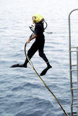 A Navy diver from Mobile Diving Salvage Unit One enters the water from a diving platform. The diver, wearing a Mark 12 dive helmet is studying the wreck of the World War II Japanese merchant ship KIZUGAWA MARU as part of Project Sea Mark, a four-year undersea survey and mapping study of naval historic sites. The study is being conducted in conjuction with the U.S. Park Service's Submerged Cultural Resource Unit