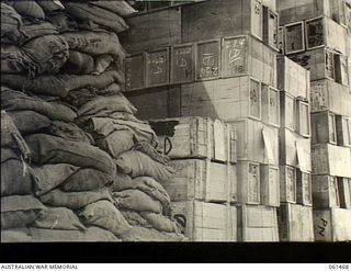 PORT MORESBY, NEW GUINEA. 1943-12-06. STACKS OF BURLAP WRAPPERS (LEFT) AND PARACHUTES IN CASES (RIGHT) AT NO. 2 SUB DEPOT, 10TH AUSTRALIAN ADVANCED ORDNANCE DEPOT