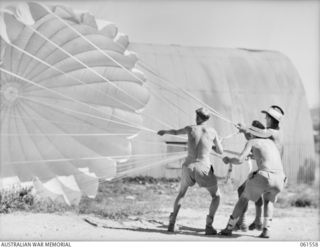 3 MILE, PORT MORESBY, NEW GUINEA. 1943-12-14. PERSONNEL OF THE 1ST AUSTRALIAN PARACHUTE REFOLDING PLATOON, AUSTRALIAN ARMY ORDNANCE CORPS, CHECKING AN AMERICAN 24 FOOT CARGO DROPPING PARACHUTE. ..