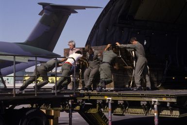 Members of the 22nd Military Airlift Squadron load building supplies into a C-5 Galaxy aircraft headed for Pago Pago, American Samoa