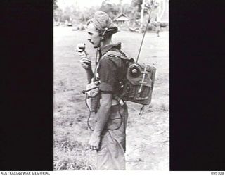 RABAUL, NEW BRITAIN, 1945-12-06. A SIGNALLER DEMONSTRATING A WIRELESS SET 108 IN ITS CARRIED POSITION DURING A DEMONSTRATION OF VARIOUS INFANTRY WEAPONS AND EQUIPMENT