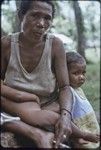 Woman smoking, sleeping infant on her lap, small girl leaning on her