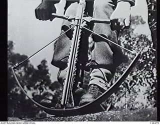 NEW GUINEA. 1943-02. SERGEANT J. W. WRIGHT, ONE OF ITS TWO DESIGNERS, DEMONSTRATING THE ARROWSPEED CROSS BOW GUN DESIGNED TO FIRE INCENDIARY, HIGH EXPLOSIVE AND OTHER TYPES OF ARROWS. (DONOR: L. J. ..