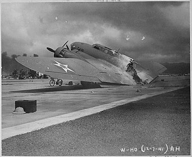 A burned B-17C aircraft rests near Hangar Number Five, Hickam Field, following the attack by Japanese aircraft. Pearl Harbor, Hawaii.