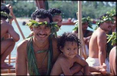 Man wearing wreath and necklaces, and child