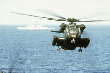 A CH-53 Sea Stallion helicopter approaches for a landing on the flight deck of the amphibious assault ship USS GUAM (LPH-9) during flight operations off the coast of Beirut, Lebanon. A French warship is underway in the background