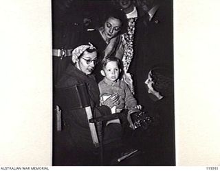 SYDNEY, NSW. 1945-09-13. MATRON JOYCE OLDROYD-HARRIS, FORMERLY MATRON OF THE RABAUL GOVERNMENT HOSPITAL, REUNITED WITH HER FAMILY AT MASCOT AERODROME ON HER ARRIVAL BACK IN AUSTRALIA AFTER BEING A ..