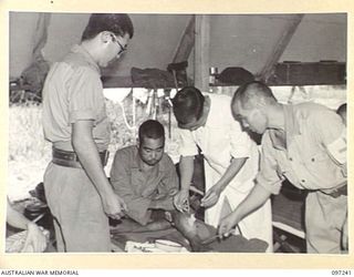 BOUGAINVILLE. 1945-09-28. A JAPANESE ORDERLY DRESSING THE LEG WOUND OF A JAPANESE SOLDIER WOUNDED IN THE BOUGAINVILLE FIGHTING. SICK AND WOUNDED PATIENTS ARE BEING CARED FOR BY JAPANESE MEDICAL ..