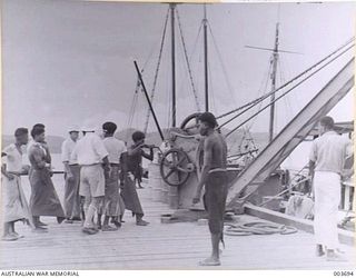 PORT MORESBY - PAPUAN NATIVES UNLOADING SHIP AT JETTY, THOUGH SMALL, THEY ARE WIRY AND STRONG. I SAW ONE BOY CARRY THREE 160 LB BAGS OF COPRA THE LENGTH OF THE JETTY AND DUMP THEM ON A HEAP BEING ..