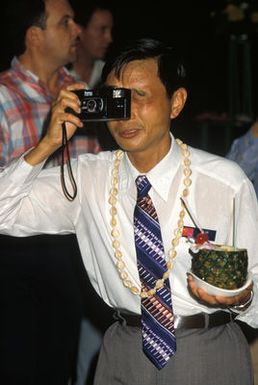 A member of the Chinese People's Liberation Army Air Force Song and Dance Troupe takes a photograph at the Hickam Officer's Club during a luau held in the troupe's honor. The troupe is here on the final stop of its US tour