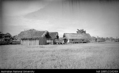 Several buildings with people sitting in shade