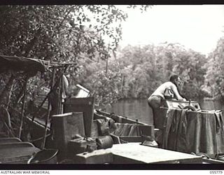 MOROBE, NEW GUINEA. 1943-08-13. UNITED STATES SMALL SHIPS SECTION, TUCKED AWAY IN THEIR DAYTIME HIDEOUT. SHOWN ARE: MR C. F. MCCLAUSLAND, CHIEF ENGINEER (LEFT); MR M. J. GILMORE, SALVAGE MASTER