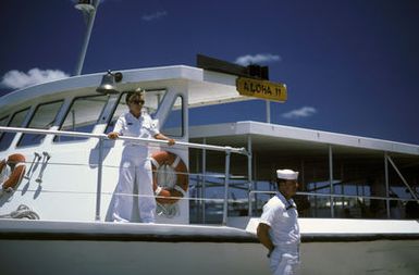 Quartermaster 3rd Class Laura Hussey stands by to coxwain one of the Navy's shuttle boats that take passengers out to the USS ARIZONA Memorial. Engineman 3rd Class Greg Orsik stands by to assist passengers in boarding the boat