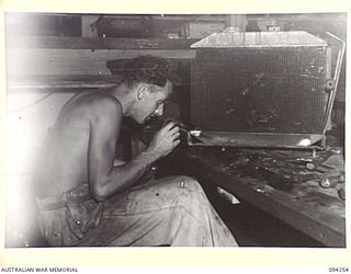 PALMALMAL PLANTATION, NEW BRITAIN. 1945-07-21. CORPORAL A.L. WOODFORD, 1 INFANTRY TROOPS WORKSHOP, REPAIRING RADIATORS FOR USE IN RECONDITIONED JEEPS