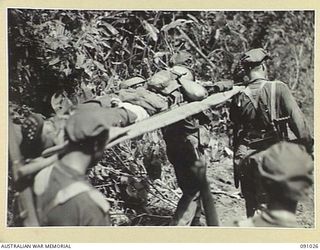 BOUGAINVILLE. 1945-04-17. A 24 INFANTRY BATTALION CASUALTY BEING CARRIED BY STRETCHER BEARERS FROM THE HATAI JUNCTION - BUIN ROAD AREA DURING THE BATTALION'S ATTACK