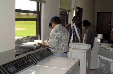 US Air Force (USAF) members from the 36th Civil Engineer Squadron (CES), from Andersen Air Force Base (AFB), Guam, install washers and dryers in a temporary laundry facility created after the damaging super-typhoon Pongsona hit the island