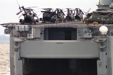 A starboard quarter view of the amphibious assault ship USS SAIPAN (LHA 2) with CH-53E Super Stallion and CH-46 Sea Knight helicopters parked on the flight deck during NATO Exercise NORTHERN WEDDING '86