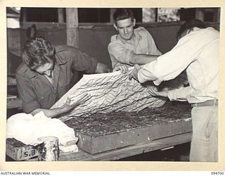 YALU, NEW GUINEA. 1945-08-03. AT THE NEW GUINEA TRAINING SCHOOL, CORPORAL S.H. EDDOWES (1) AND LIEUTENANT H. HEYHOE (2), AIDED BY FLYING OFFICER CRAIG-SMITH (3), LIFT A COPY FROM THE MOULD MADE ..