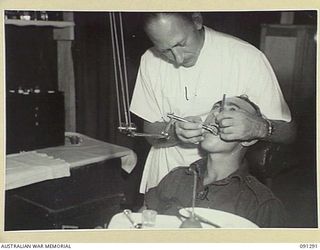 BOUGAINVILLE. 1945-04-26. PRIVATE L.J. DOUGLAS, 61 INFANTRY BATTALION (2), RECEIVING DENTAL TREATMENT FROM CAPTAIN H.F. SUDHOLZ (1), AT 2/3 CONVALESCENT DEPOT