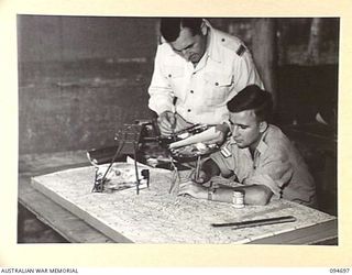 YALU, NEW GUINEA. 1945-08-03. AT THE NEW GUINEA TRAINING SCHOOL, FLYING OFFICER CRAIG-SMITH (1), INSTRUCTS CORPORAL J.T. RIGBY (2), ON THE METHOD OF PREPARING A MAP BASE FOR MODELS