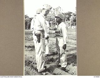 1943-03-24. NEW GUINEA. BRIG. GENERAL JOHNS PINS A MEDAL ON PRIVATE 1ST CLASS JULIUS FRANKLIN AT A CEREMONIAL PARADE IN NEW GUINEA. FRANKLIN DIVED INTO A RIVER TO RESCUE A FIGHTER PILOT WHOSE PLANE ..
