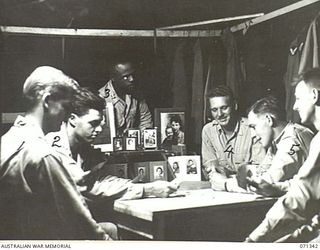 LANGEMAK BAY, NEW GUINEA, 1944-03-20. MEMBERS OF THE 870 UNITED STATES AVIATION ENGINEER BATTALION PLAYING A CARD GAME. SHOWN ARE: LIEUTENANT G.H. SMITH ( ); LIEUTENANT B.K. LLOYD (2); CHAPLAIN ..