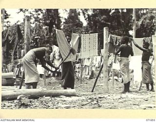 LAE, NEW GUINEA. 1944-03-25. NATIVE BOYS HANGING WASHING ON THE LINES AT THE AUSTRALIAN NEW GUINEA ADMINISTRATIVE UNIT NATIVE COMPOUND