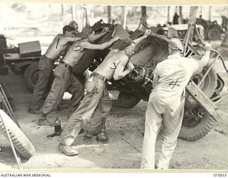 ALEXISHAFEN, NEW GUINEA. 1944-09-13. TROOPS OF THE 133RD BRIGADE WORKSHOPS, TURNING A JEEP ON ITS SIDE FOR SERVICING AT THE UNIT MOTOR TRANSPORT SUBSECTION. IDENTIFIED PERSONNEL ARE:- NX161395 ..