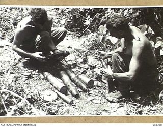 WANDOKAI, NEW GUINEA. 1944-01-01. WX11709 PRIVATE E. T. CARROLL (1) AND WX5921 PRIVATE R. A. HARTNETT OF THE 9TH DIVISION SALVAGE UNIT DISPLAY VARIOUS TYPES OF AMMUNITION WHICH WAS ABANDONED BY THE ..