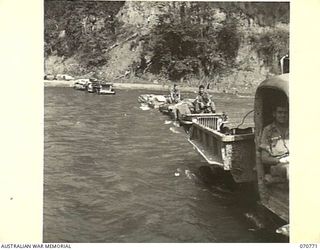 WAMPIT, NEW GUINEA, 1944-03-02. A SUPPLY CONVOY BEING TOWED ACROSS THE RIVER AT WAMPIT BY A FERRY TRUCK FROM HEADQUARTERS, COMMANDER ROYAL ENGINEERS (A.I.F.). THE TOWING TRUCK SAVES REMOVING ..