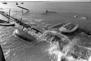 A view of a dock that was destroyed and several small boats that were damaged or capsized in Hickam Harbor during by Hurricane Iwa