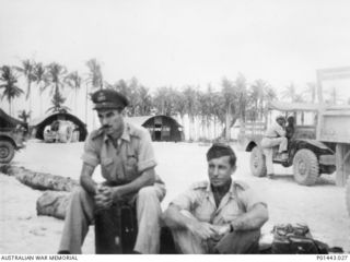 CAPE GLOUCESTER, NEW BRITAIN. 1943. SQUADRON LEADER W. (BILL) J. CLARKE, RAAF, (LEFT) AND WING COMMANDER H. ROY BOOTH, RAAF, AWAITING AIR TRANSPORT AT THE AIRFIELD. CLARKE WAS THE CHIEF SIGNALS ..