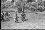 Bride price ritual: decorated men with spears charge in mock aggression, followed by others from groom's group who dance into bride's village