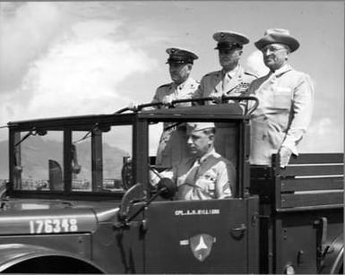 Former President Harry S. Truman stands at the back of a military truck at Marine Corps Air Station, Kaneohe Bay, Hawaii