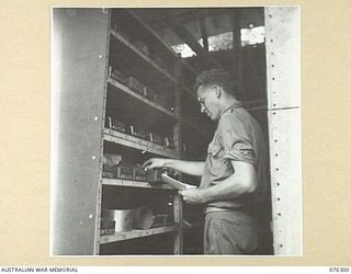 LAE, NEW GUINEA. 1944-09-27. A MEMBER OF THE 43RD FIELD ORDNANCE DEPOT CHECKING THE SUPPLIES OF SPARE PARTS IN THE RACKS OF ONE OF THE UNIT STORES