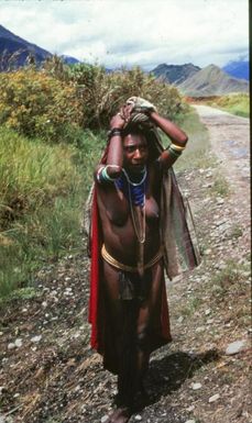 “The Woman of the Highlands, Mt. Hagen” (original caption). A woman stands on a mountain road small road.