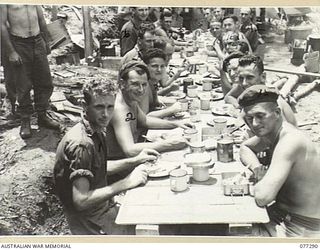 LARUMA VALLEY, BOUGAINVILLE ISLAND. 1944-11-25. PERSONNEL OF THE 224TH SUPPLY DEPOT PLATOON ENJOYING A MEAL AT THEIR CAMP NEAR HEADQUARTERS, 9TH INFANTRY BATTALION. IDENTIFIED PERSONNEL ARE:- ..