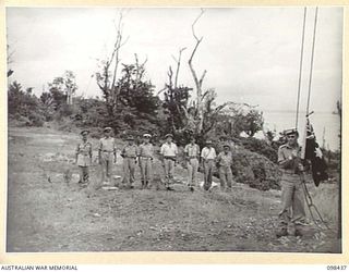 KAVIENG, NEW IRELAND. 1945-10-19. AN AUSTRALIAN ROYAL NAVY RATING FROM HMAS KIAMA ABOUT TO HOIST THE AUSTRALIAN FLAG ON A JAPANESE RIGGED FLAGPOLE AT THE AUSTRALIAN NEW GUINEA ADMINISTRATIVE UNIT ..