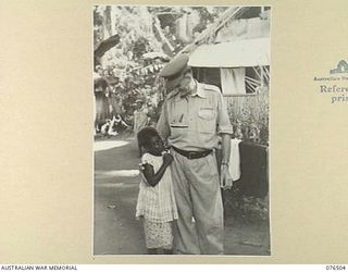 LAE, NEW GUINEA. 1944-10-18. NGX350 MAJOR E.W. JENYNS, DEPUTY ASSISTANT DIRECTOR OF NATIVE LABOUR AND OFFICER IN CHARGE, LAE BASE NATIVE LABOUR, AUSTRALIAN NEW GUINEA ADMINISTRATIVE UNIT, WITH A ..