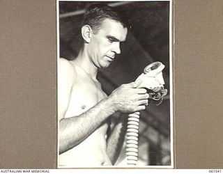 17 MILE, PORT MORESBY AREA, NEW GUINEA. 1943-12-13. WX34714 SERGEANT F. WILLIS OF THE RETURNED STORES DEPOT, 10TH AUSTRALIAN ADVANCED ORDNANCE DEPOT EXAMINES A DAMAGED RESPIRATOR TO DECIDE WHETHER ..