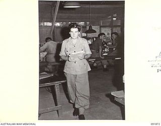 LAE, NEW GUINEA, 1945-05-16. SIGNALWOMAN H.G. MALDON, SIGNAL CLERK (1), CARRYING A BATCH OF SIGNALS FOR DISPATCH. AUSTRALIAN WOMEN'S ARMY SERVICE PERSONNEL ARE TAKING OVER THEIR NEW DUTIES IN ORDER ..