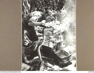 1943-09-20. NEW GUINEA. BUSO RIVER - LAE AREA. STAFF SERGEANT JIM WADE OF NEWCASTLE, N.S.W. INSPECTS FOOD BEING COOKED BY A PIONEER UNIT. (NEGATIVE BY H. DICK)