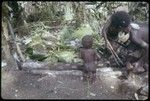 Pig festival, pig sacrifice, Torpai: Kinimp watches Moramp and another woman prepare food in ancestral shrine