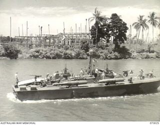 SEK ISLAND, NEW GUINEA. 1944-04-27. THE VIEW FROM THE CORVETTE HMAS BUNDABERG TOWARDS ALEXISHAFEN, SHOWING WRECKED BUILDINGS AT THE BACKGROUND, AND A UNITED STATES NAVY MTB (MOTOR TORPEDO BOAT) IN ..