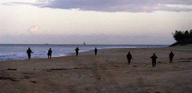 With US Navy warships on the horizon, US Marines of the 13th Marine Expeditionary Unit, Camp Pendleton, California from Boat Co., Foxtrot 21, Camp Pendleton, California clear the beach for an amphibious assault during exercise RIMPAC '98