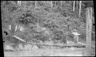 Sarah Chinnery with a man crossing a wire rope bridge, Bulolo River [?], New Guinea, 1933