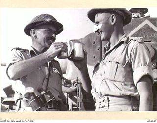 1943-01-21. PAPUA. BUNA. AMERICAN RE-INFORCEMENTS MOVE UP TO THE FRONT LINE, PAUSE AT A TRANSIT CAMP FOR A MEAL. (NEGATIVE BY BOTTOMLEY)
